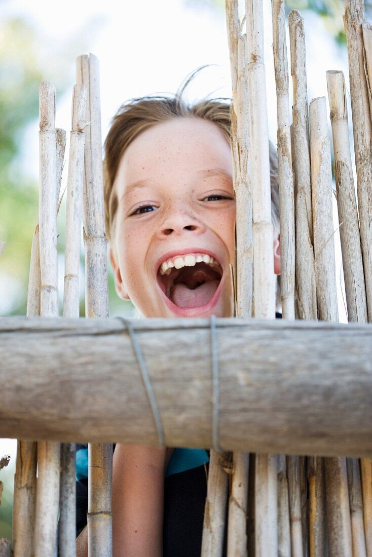 Lachender Junge hinter einem Zaun