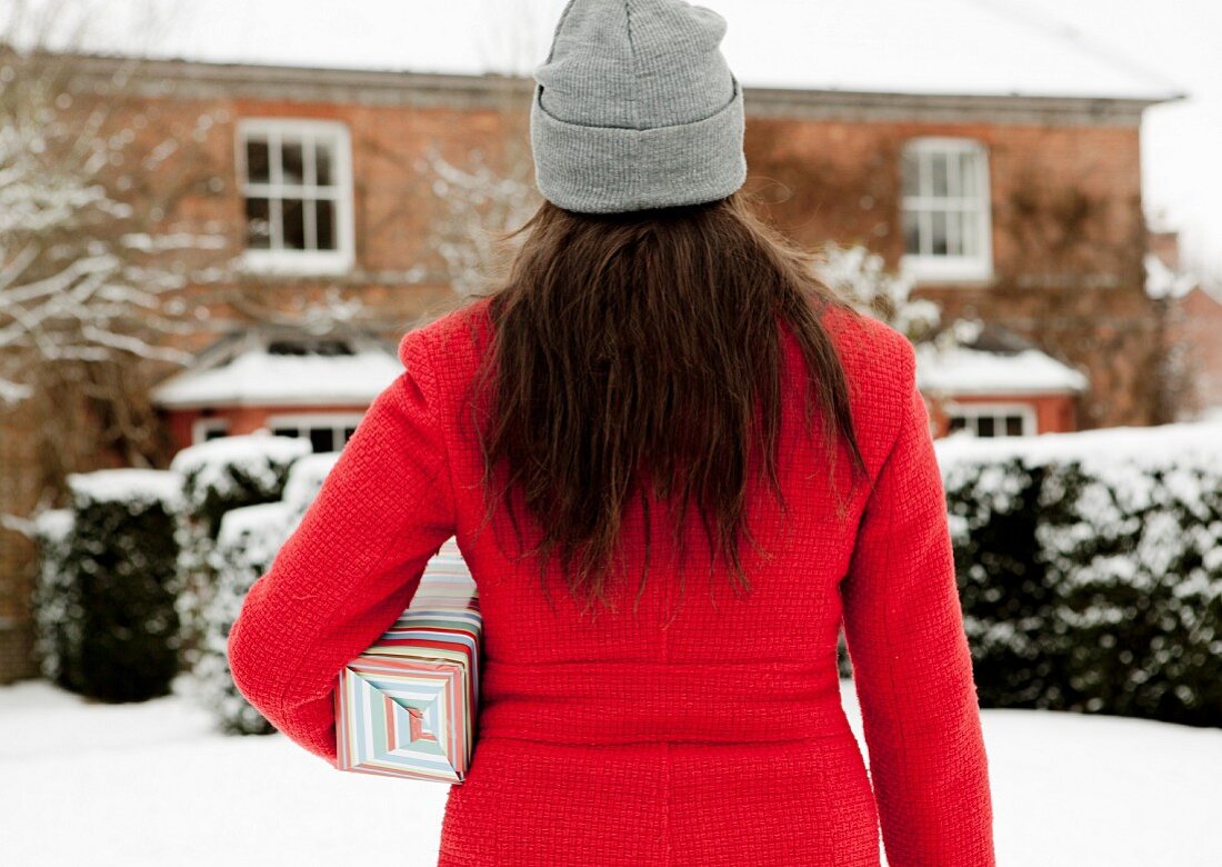 Woman carrying wrapped gift in snow