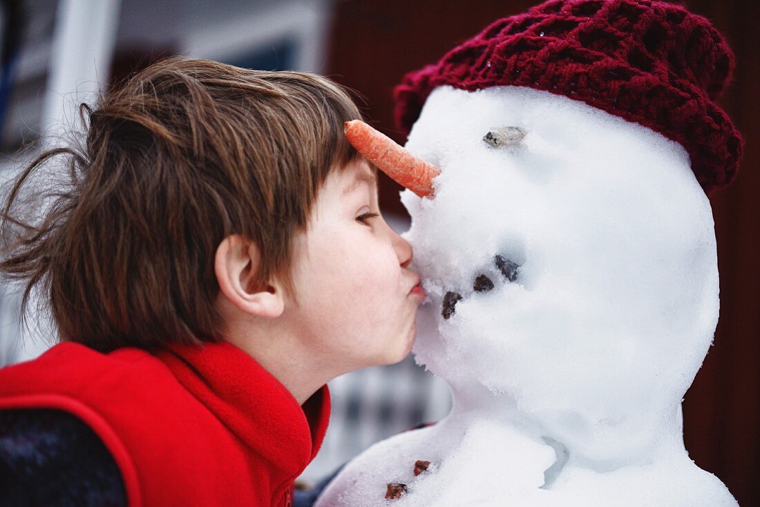 Kleiner Junge küsst Schneemann