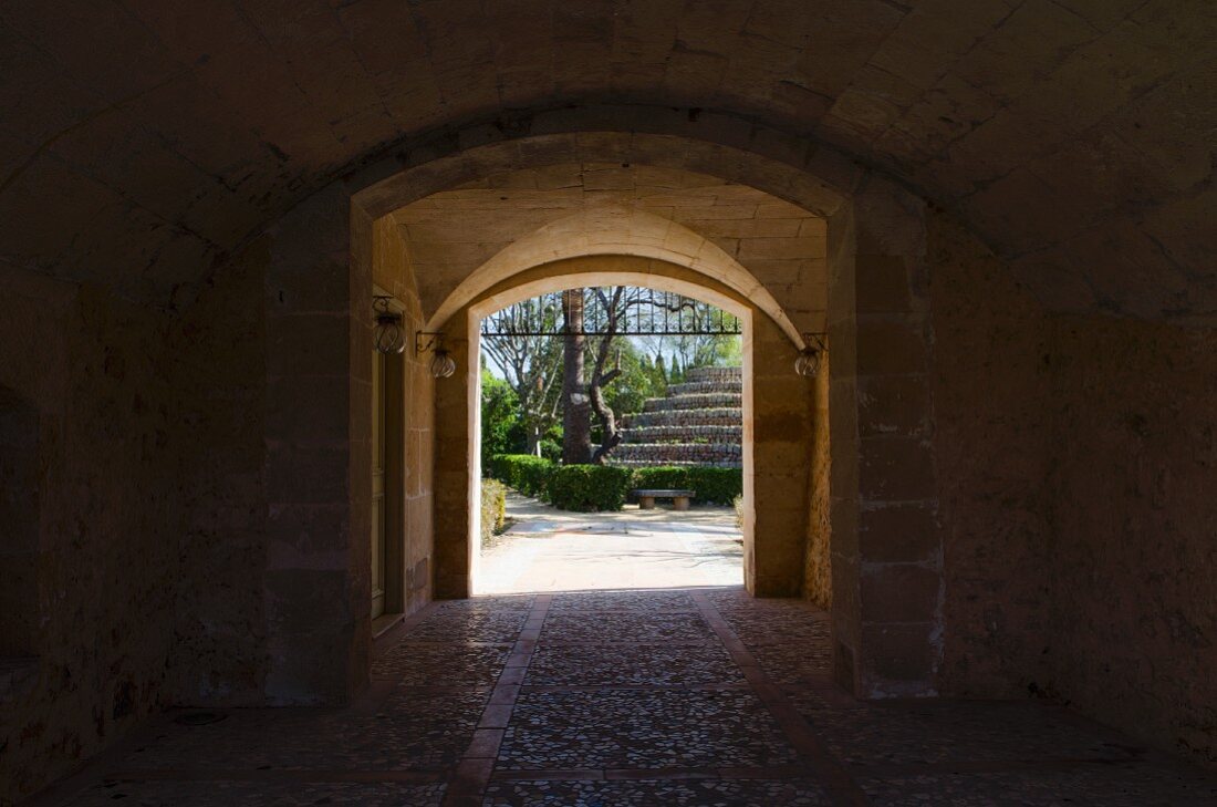 Einfahrt mit alter Gewölbedecke und Blick in Garten