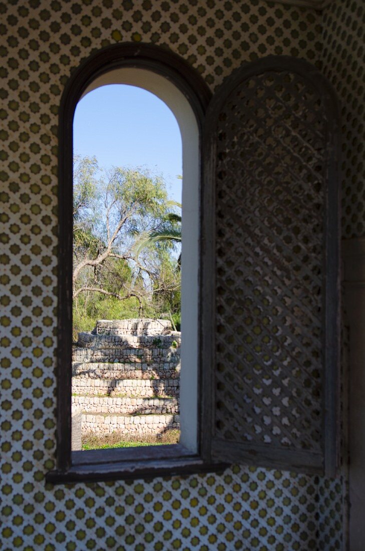 Blick durch offenes Fenster in mediterranen Garten