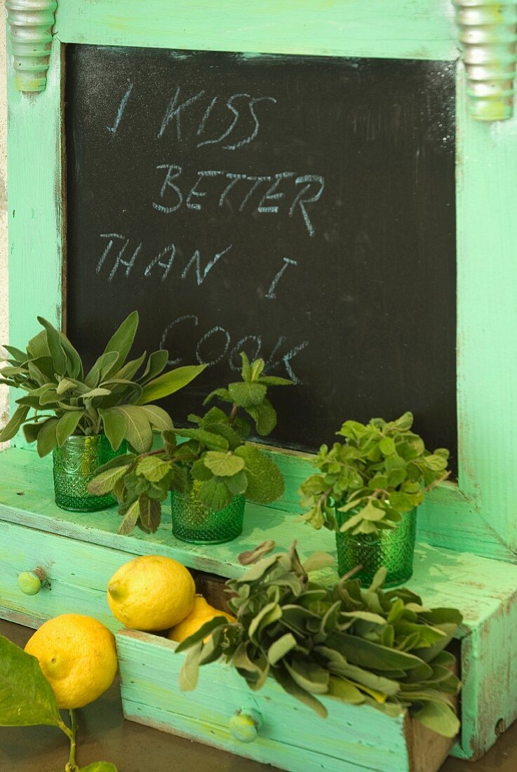 Fresh herbs and lemons on a wooden turquoise shelf and a built in chalkboard