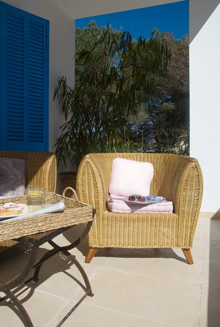 Comfortable wicker armchair and side table on Mediterranean veranda