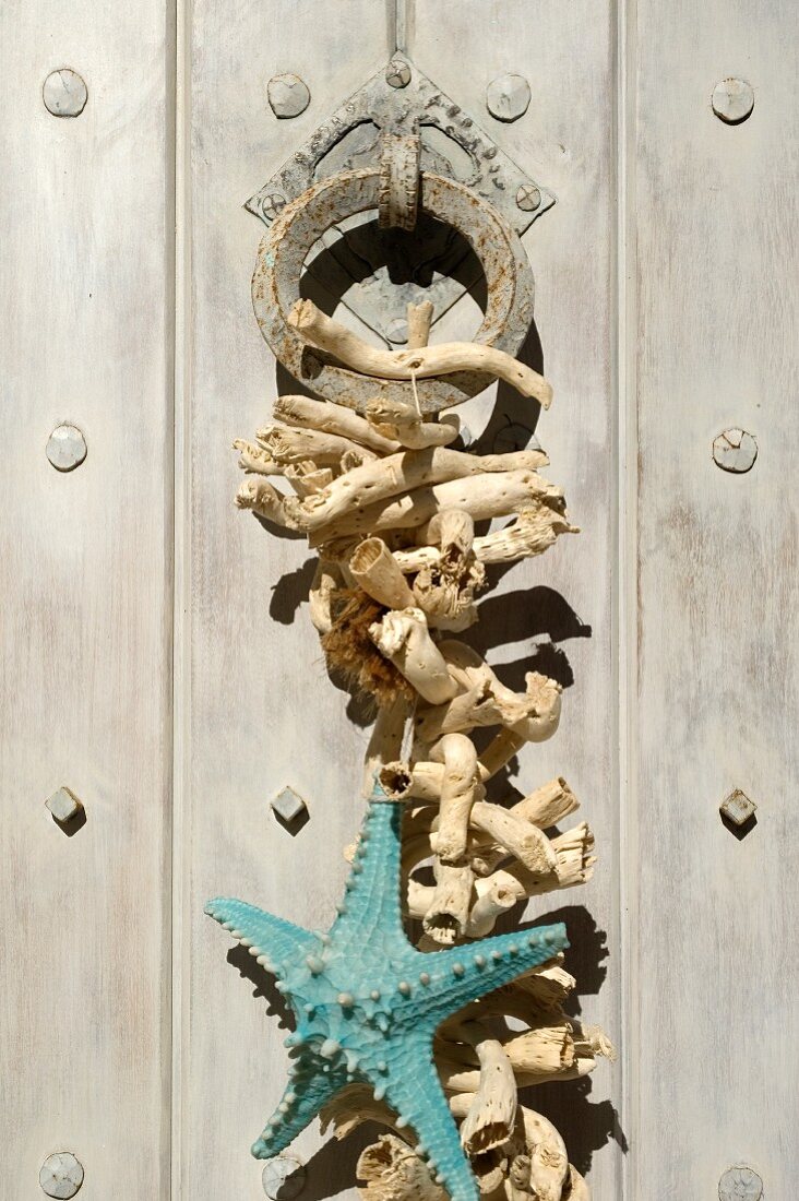 Starfish and weathered pieces of wood hanging on door knocker