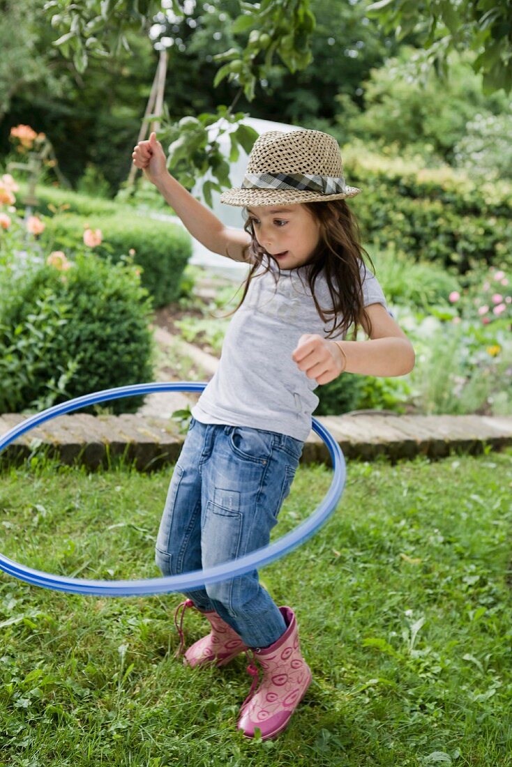 Mädchen spielt mit Hula Hoop Reifen im Garten