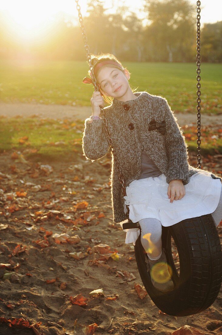 Mädchen sitzt auf einer Gummireifenschaukel im Park