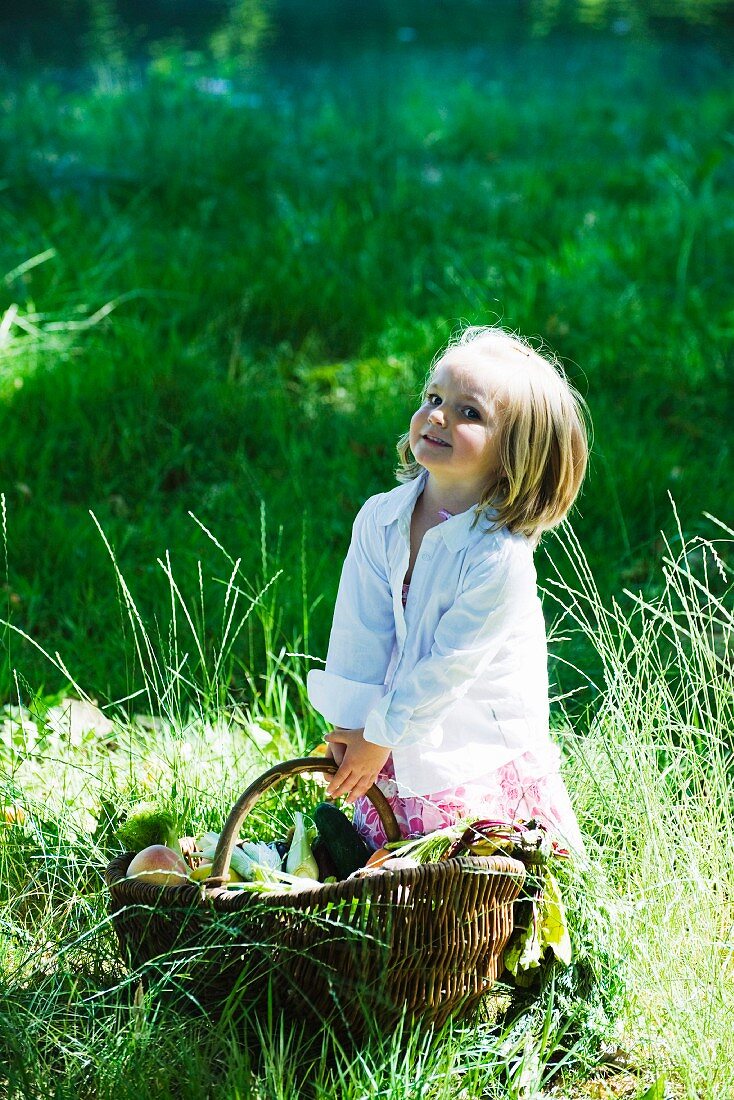 Kleines Mädchen mit Picknickkorb auf der Wiese
