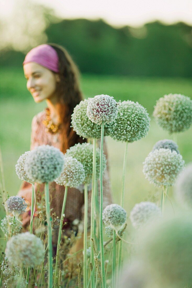 Young woman, focus on allium flowers in foreground