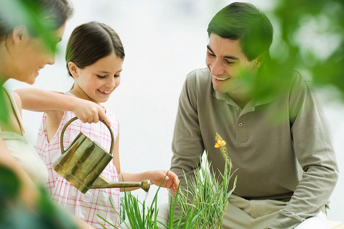 Familie im Garten - Kind giesst Blumen