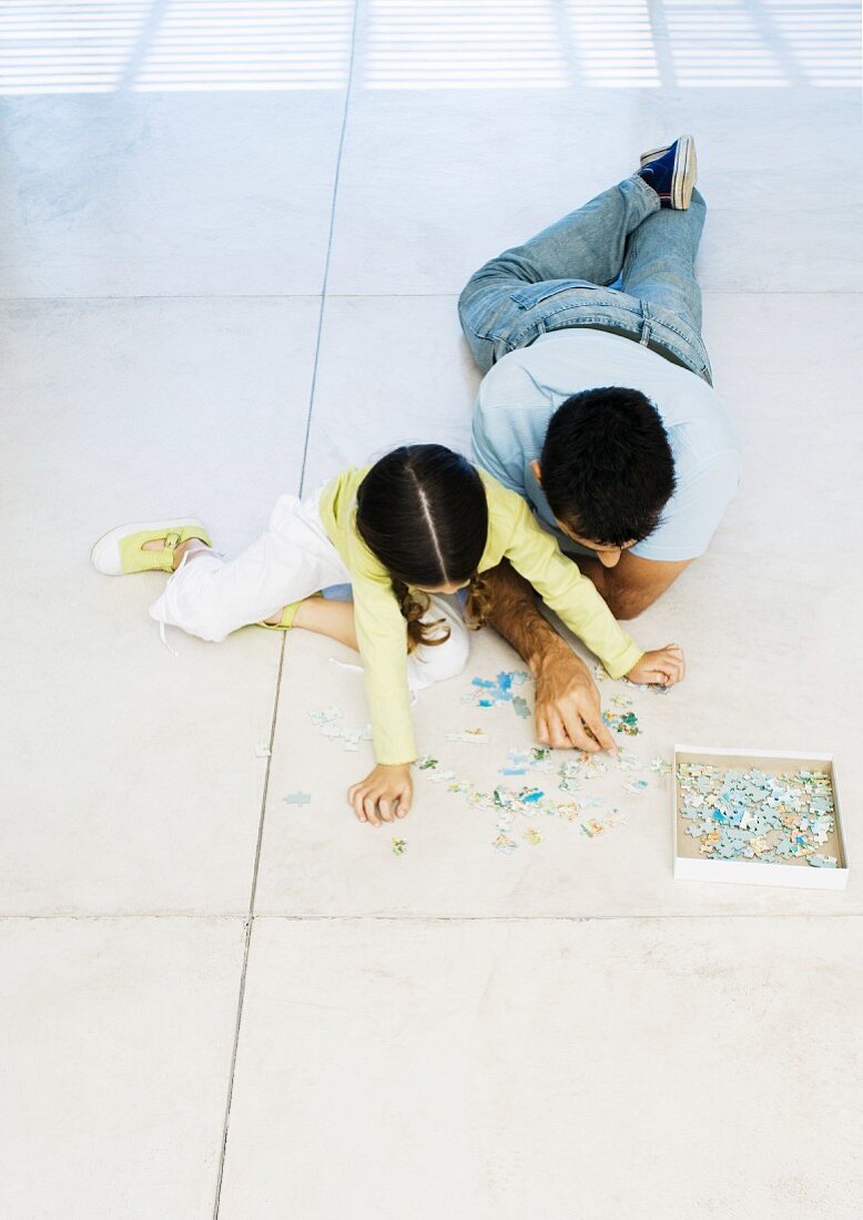 Vater und Tochter auf dem Boden beim Puzzle spielen
