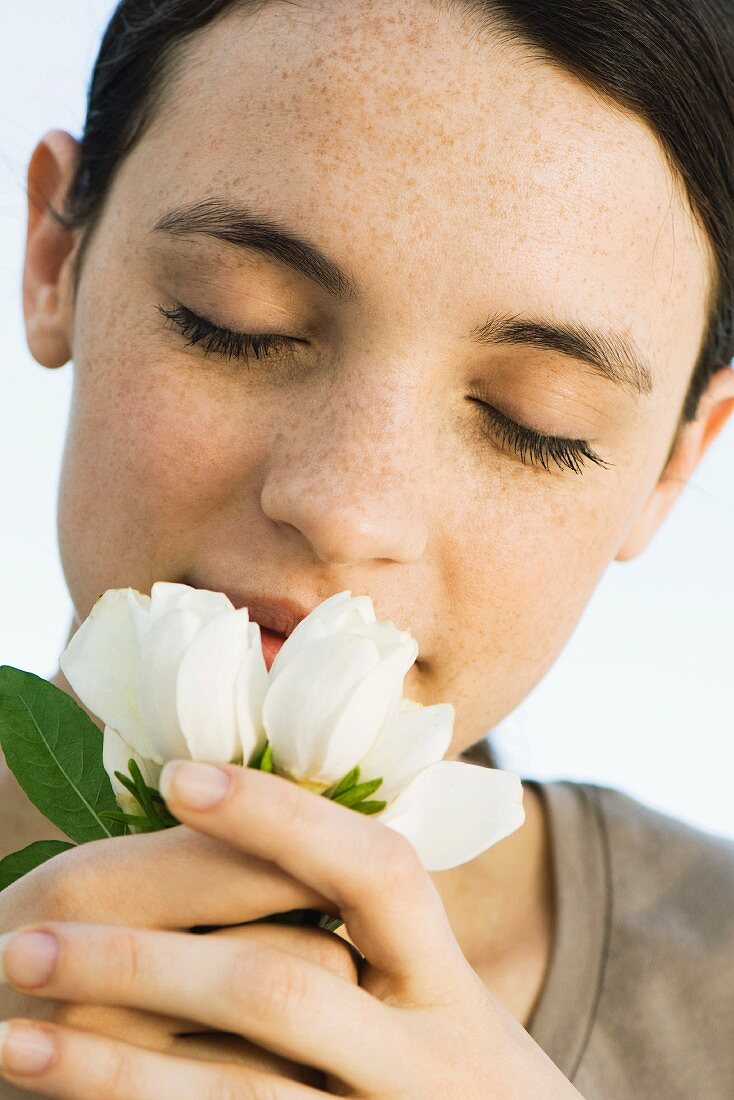 Frau riecht verträumt an Blumen