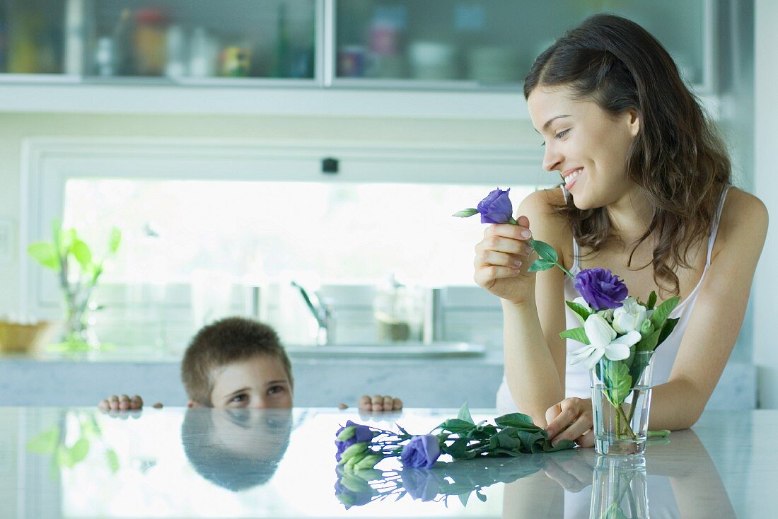 Mutter und Kind in der Küche mit Blumenvase auf der Theke
