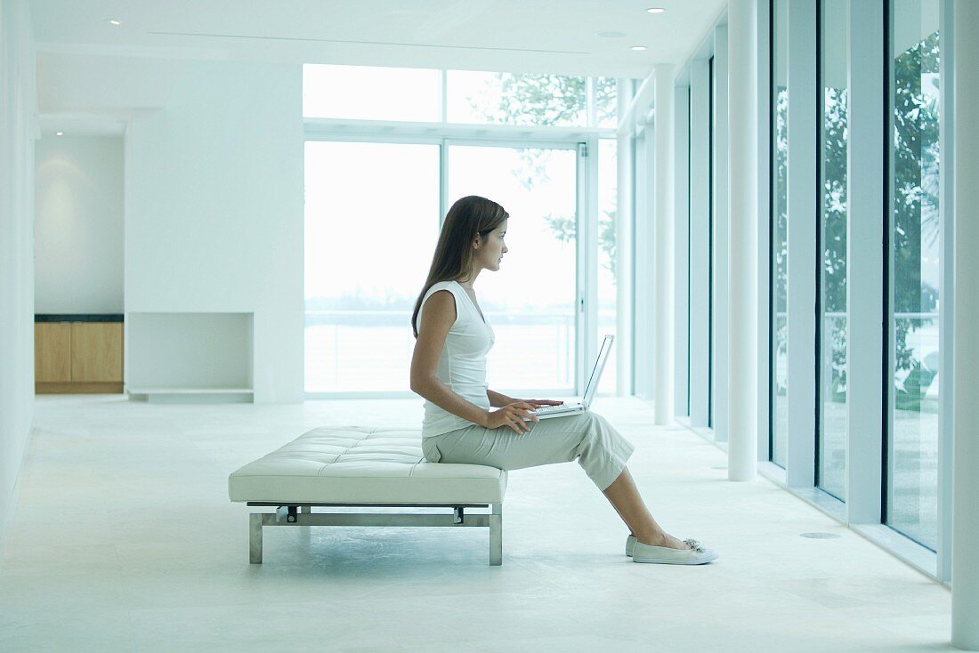 Frau sitzt auf Lederliege in minimalistischem Raum