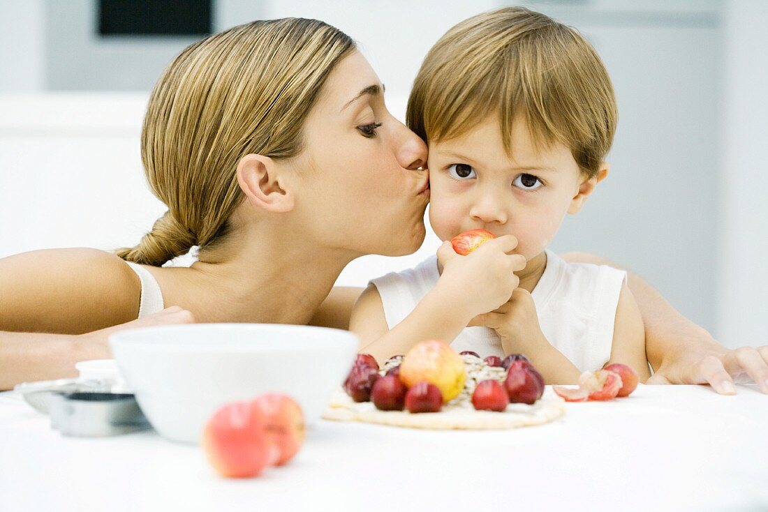 Mutter mit kleinem Sohn am beim Essen eines Obstdesserts