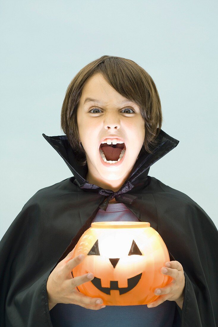 Junge im Halloweenkostüm mit geschnitztem Kürbis