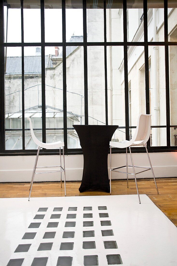 Schwarze Theke und weiße Barhocker im Designerstil vor Fenster eines Vorraumes