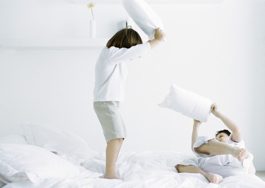Boys having pillow fight on bed