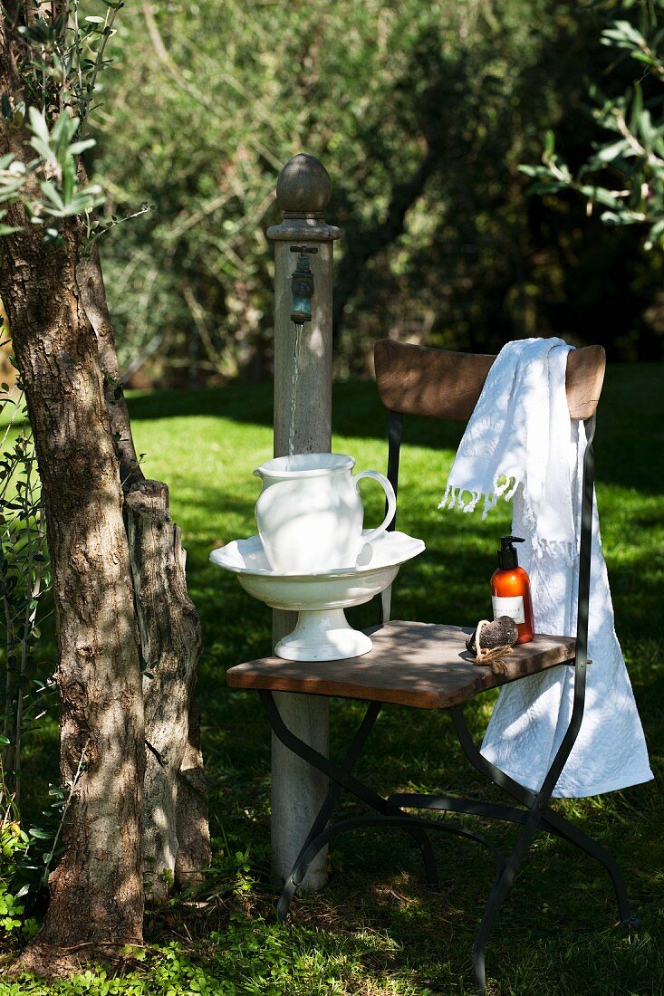 Waschschüssel und Porzellankanne auf Stuhl im Garten