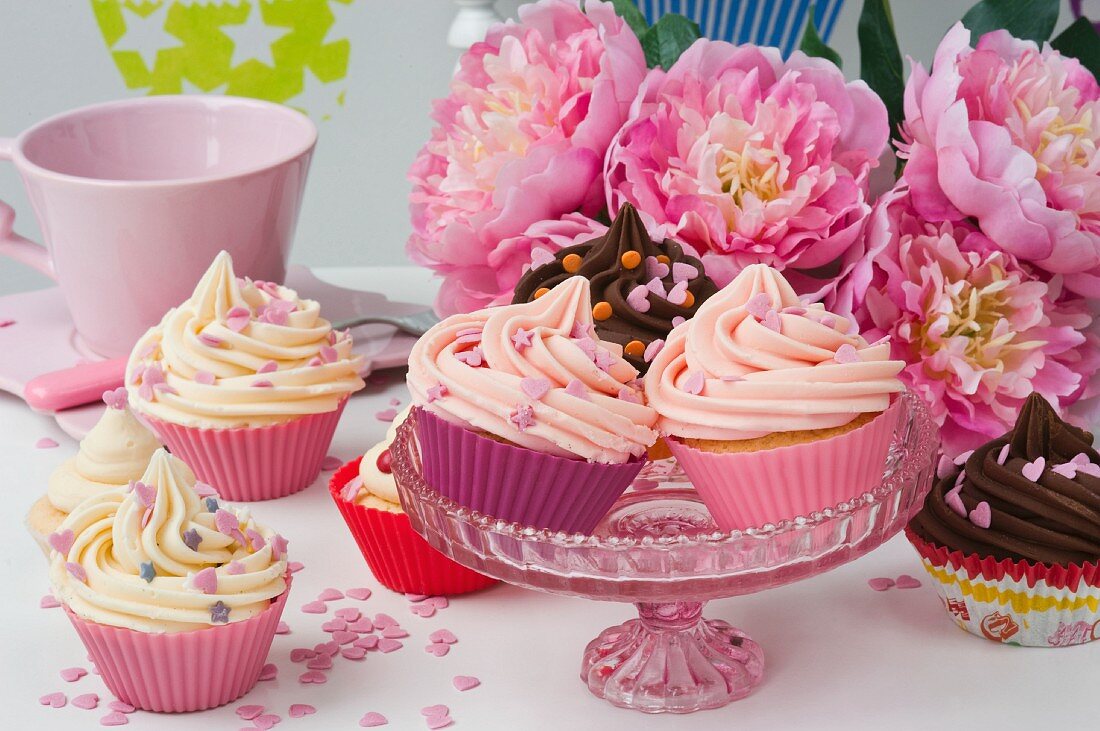 Desserts in bunten Förmchen auf Kuchenschale und Blumendeko