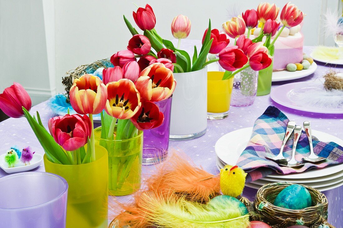 Bunte, geschmückte Tafel mit Blumensträussen und farbiger Osterdeko