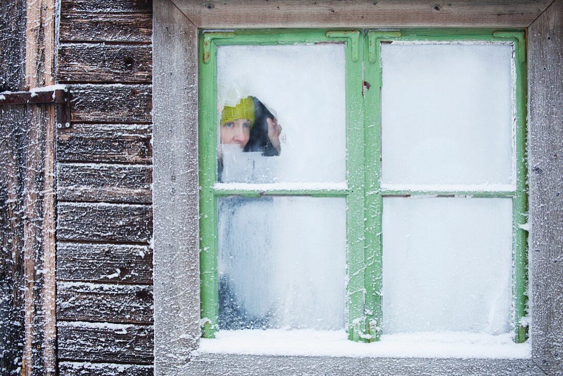 Woman peering through icy window