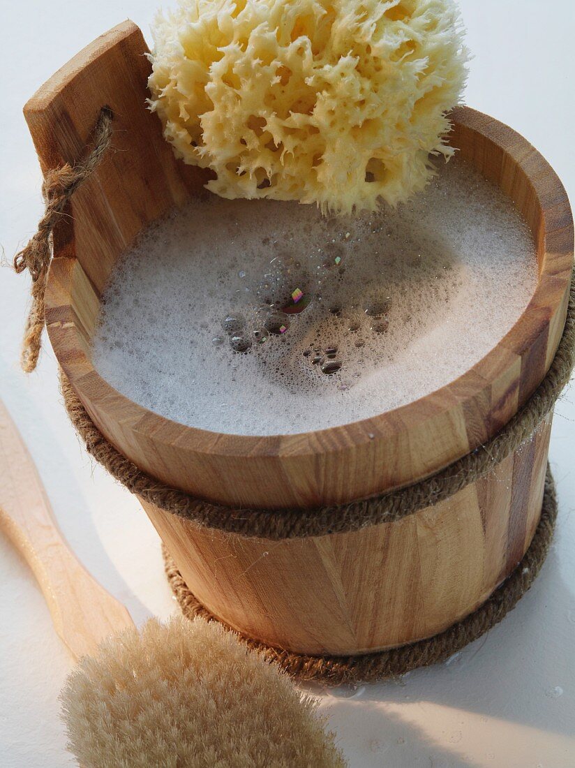 Wooden bucket of soapy water and bath sponge