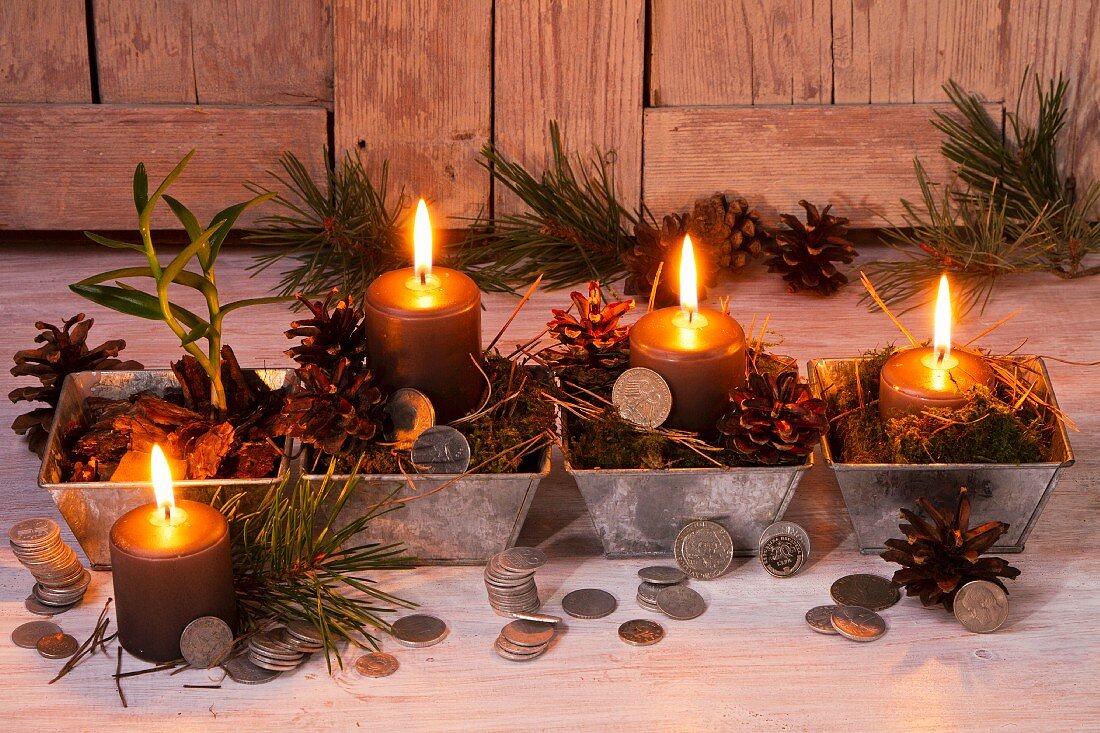 Weihnachtsdeko mit Kerzen, Pinienzapfen und Münzen
