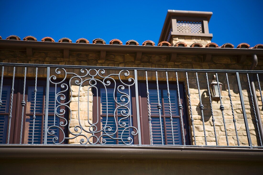 Toskanisches Wohnhaus aus Naturstein mit schmiedeeisernem Geländer vor dem Balkon