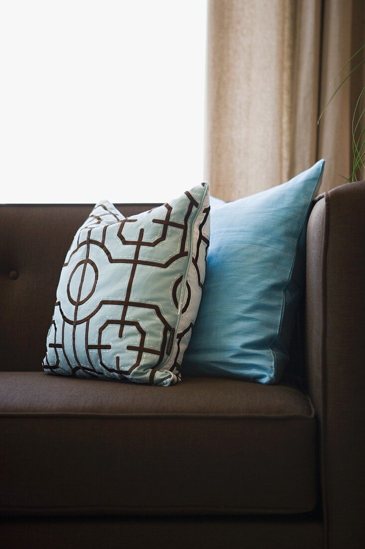 Detail blue throw pillows on chocolate brown sofa
