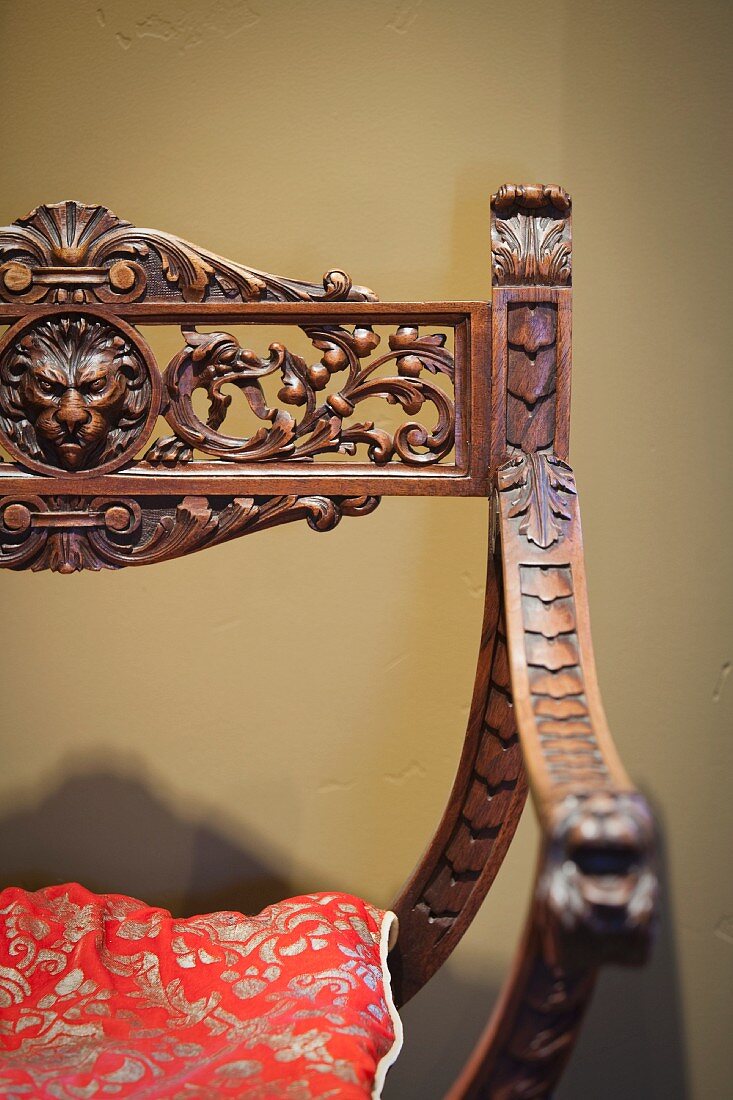Antiker Armlehnstuhl mit kunstvollen Schnitzereien und losem Polster