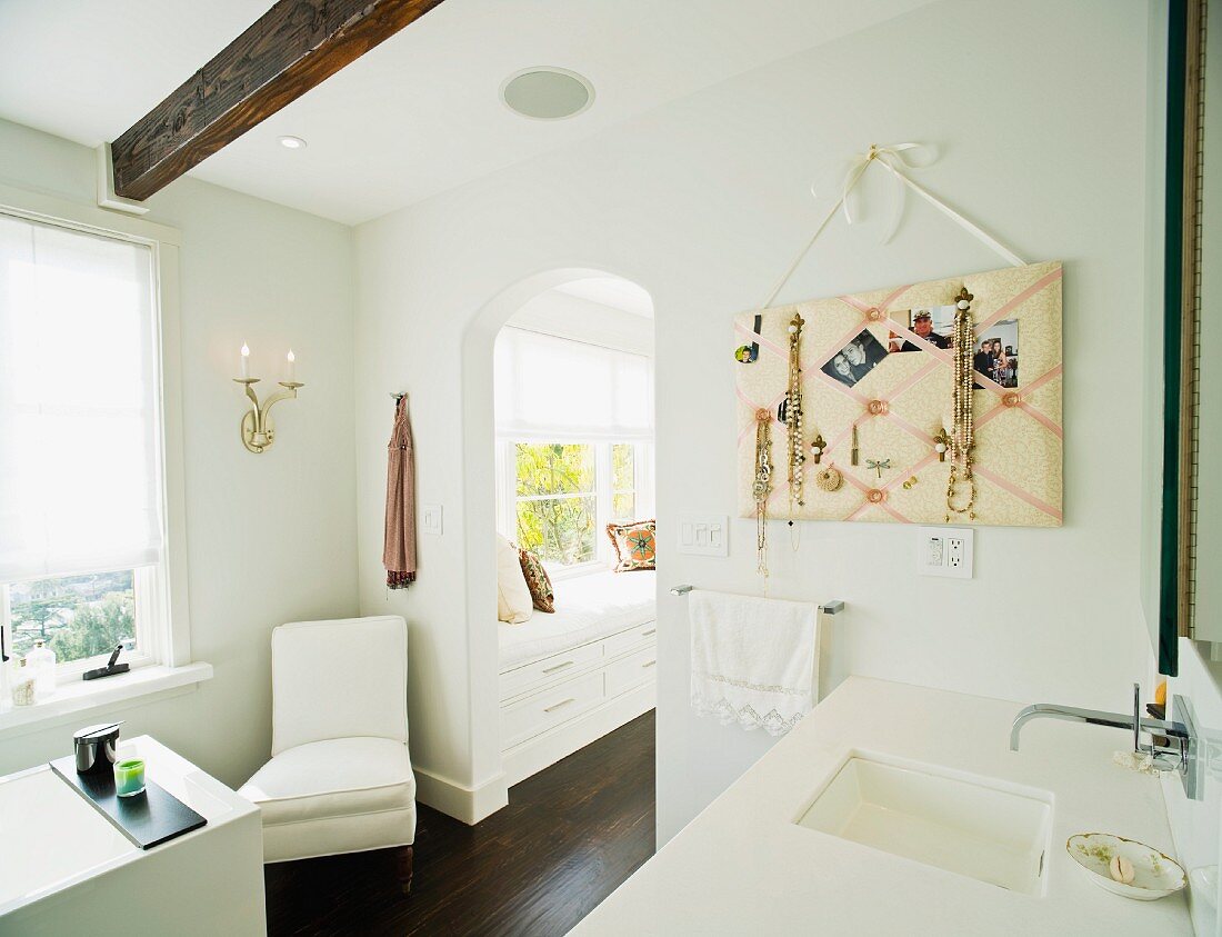 Modernes Bad mit Elementen im Landhausstil und Blick durch Rundbogen auf Sitzbank unter dem Fenster