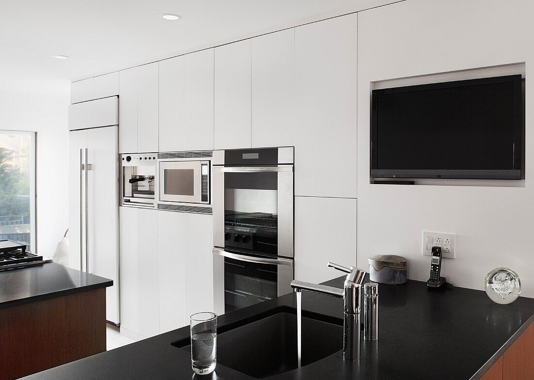 A white fitted kitchen with a black work surface
