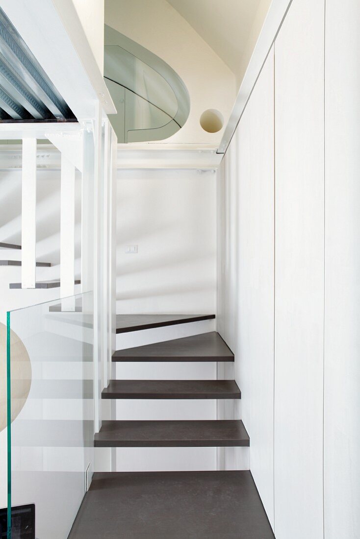 Narrow staircase with floating wooden treads fixed to stairwell walls