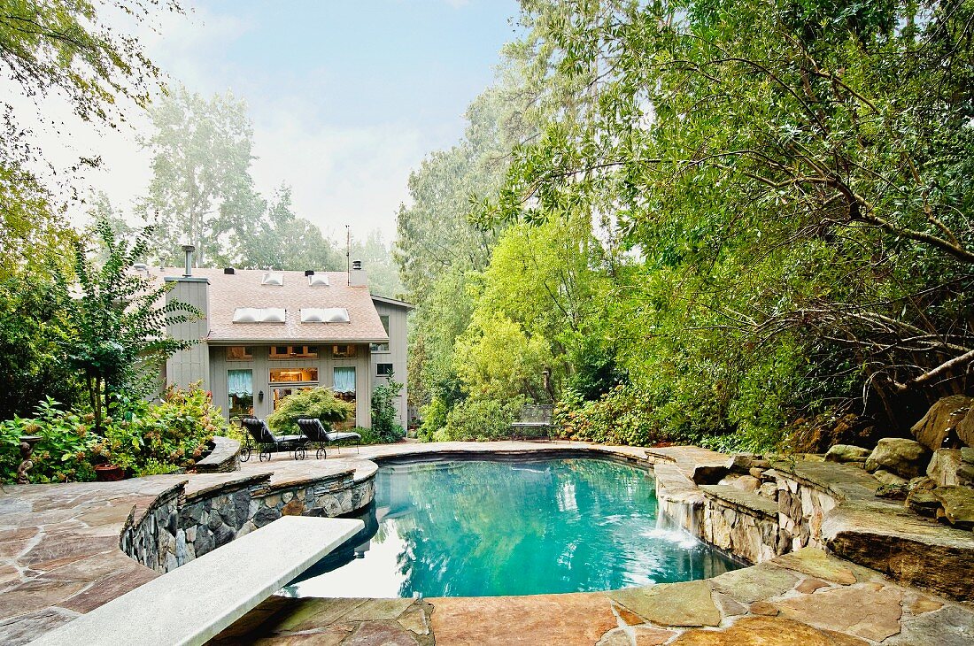 Garten mit Pool in organischer Form mit Natursteineinfassung vor Einfamilienhaus