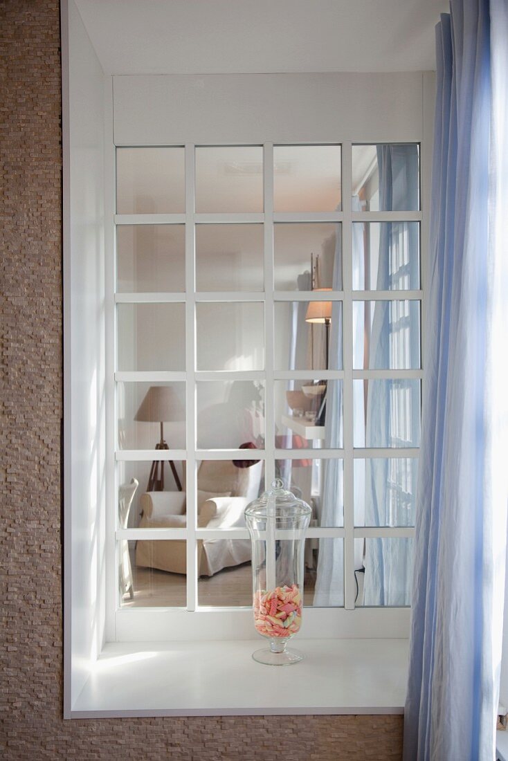Blick durch Sprossenfenster einer Loggia in Loungeecke mit Sessel