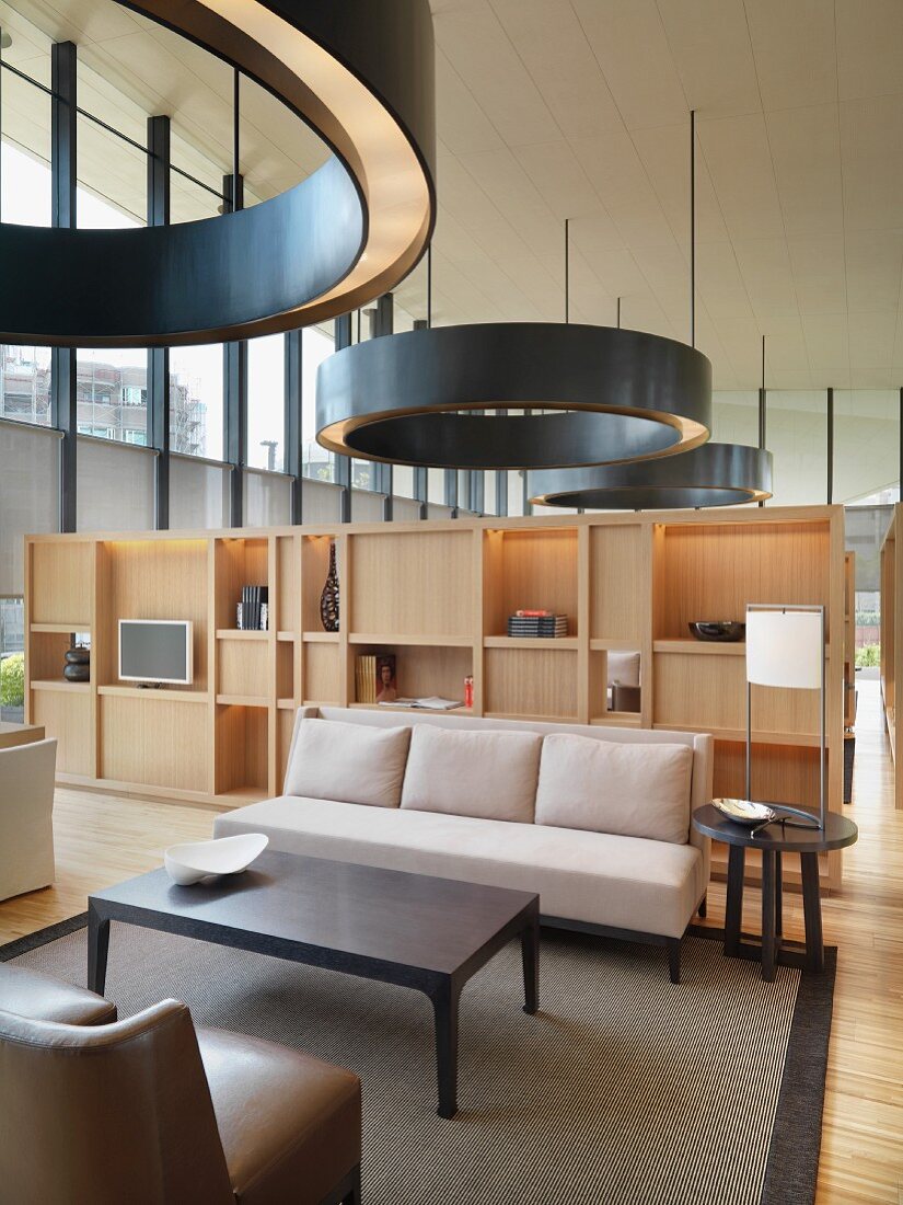 Kreisförmige Hängelampen über Sofagarnitur und Wandschrank als Raumteiler im offenen Wohnraum