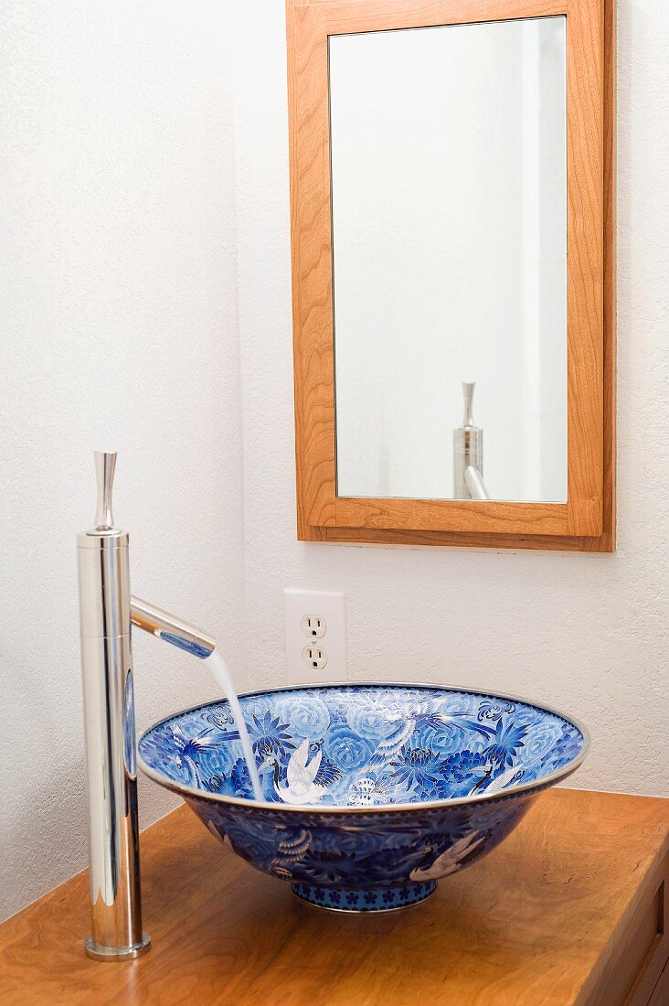 Traditionelle Waschschüssel mit blauem Muster auf Holzplatte montiert und Designer Armatur
