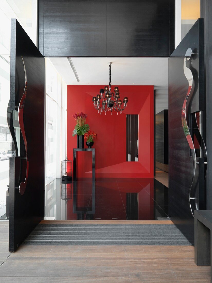 Blick durch offene Flügeltür in modernen Vorraum auf rote dreidimensionale Wand