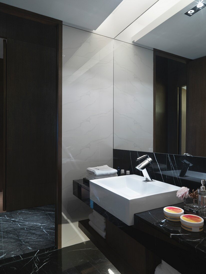Waschtisch vor vollflächigem Wandspiegel mit indirekter Deckenbeleuchtung im Designer Bad
