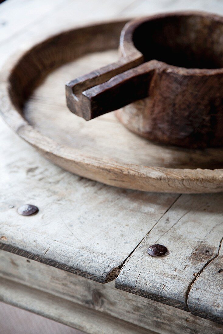 Altes Metallkännchen auf Holzschale und Tisch aus verwitterten Holzbrettern