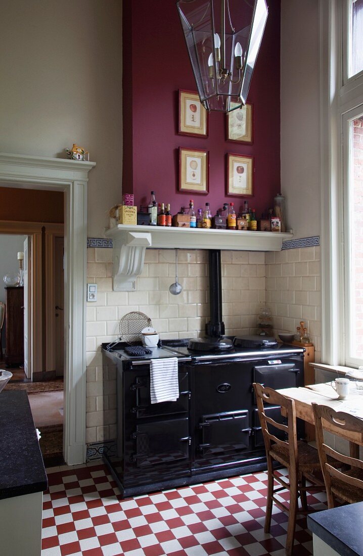 Black Aga range on red and white chequered floor in corner of rustic kitchen