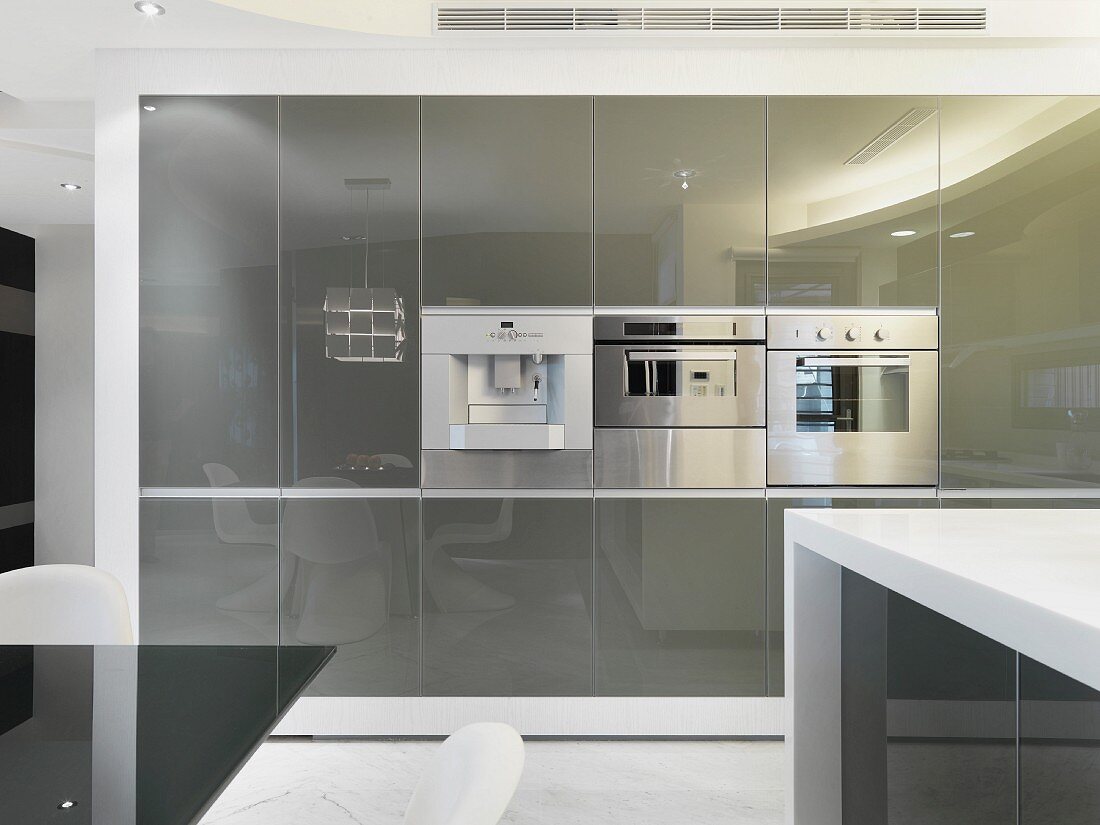 Contemporary kitchen cupboards with reflective doors and stainless steel fitted appliances