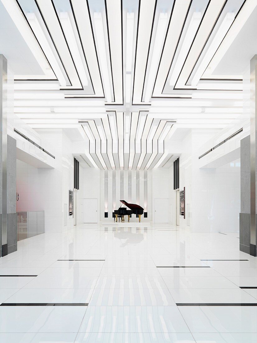 Weisser minimalistischer Raum mit Lichtbändern an Decke und Blick auf Klavierflügel