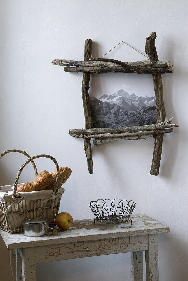 Woven bread basket and rustic driftwood picture frame on white wall