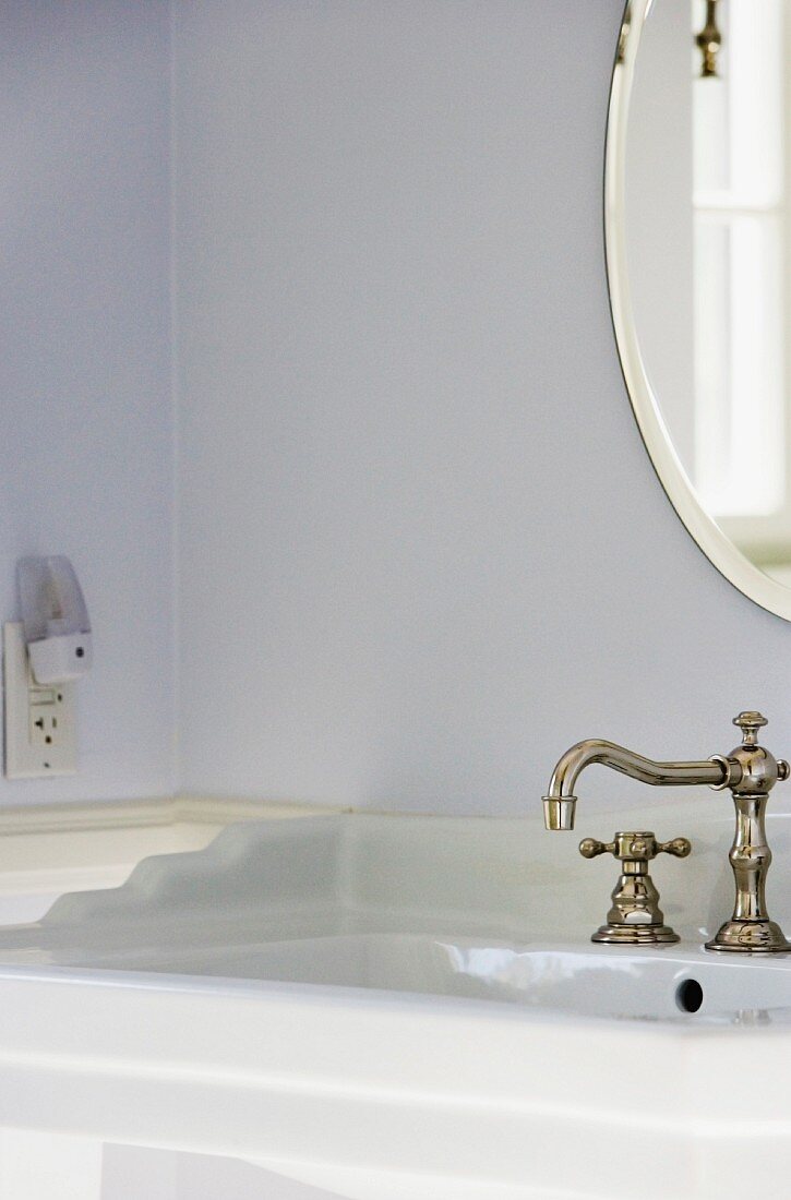 Waschbecken mit Vintage Wasserhahn, darüber ovaler Spiegel
