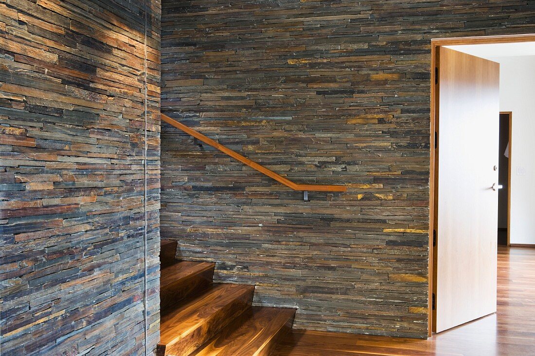 Treppenraum mit Treppe aus dunklem Holz und Steinwänden