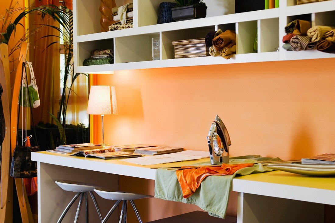 Arbeitstisch und Hängeregal vor orange getönter Wand