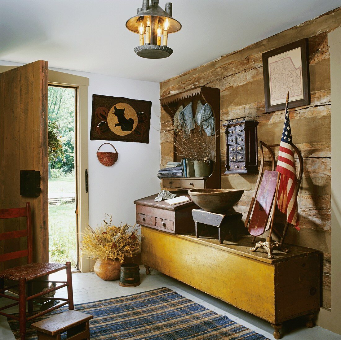 Hallway with rustic, log-cabin-style wooden wall, long wooden trunk and Post Revolutionary American antiquities