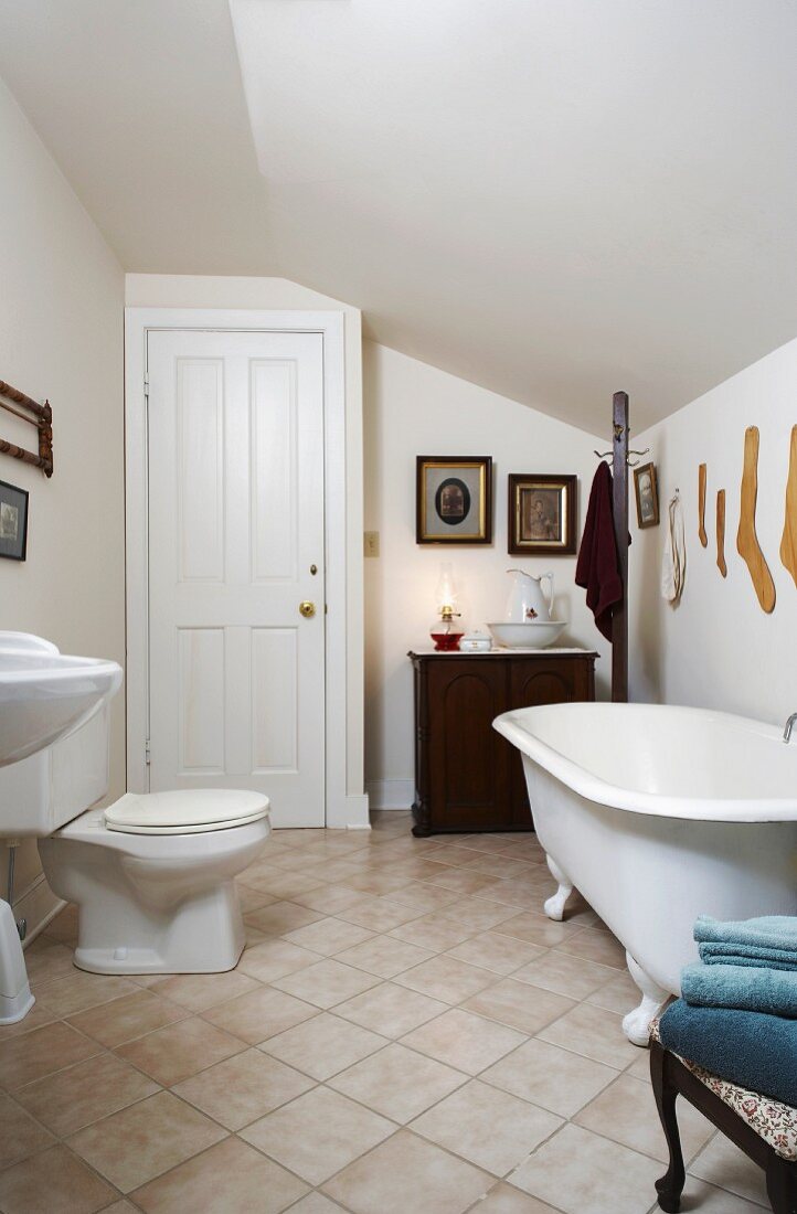 Renovated bathroom in attic with modern toilet and antique bathtub