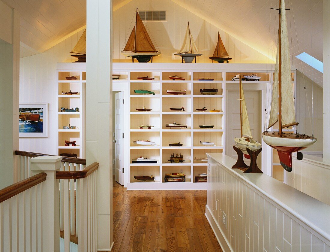 Attic room with white shelving holding large collection of model boats